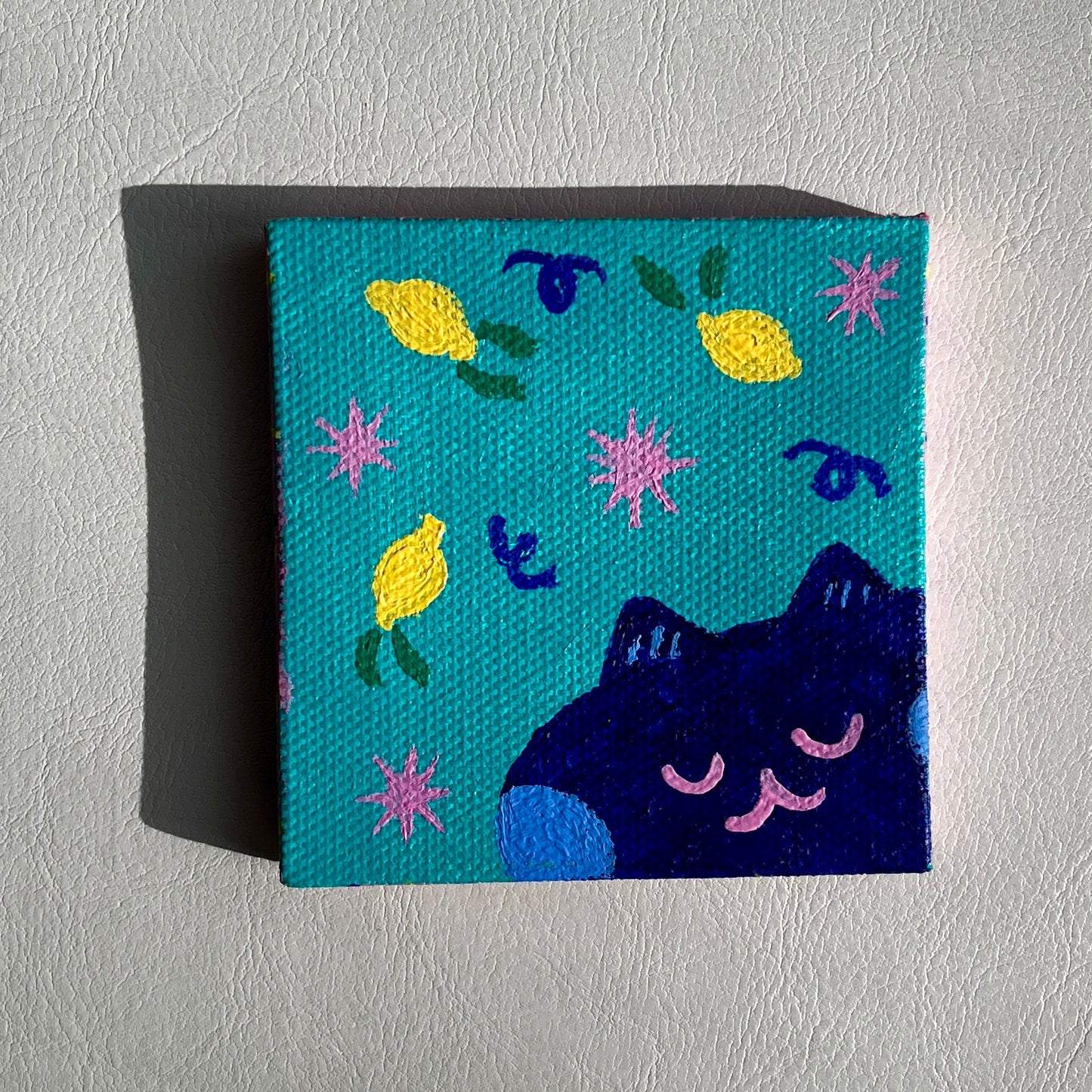 square painting with a navy blue cat with blue cheeks and lemons, pink stars, teal background 